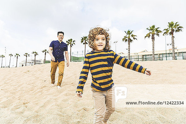 Spain  Barcelona  father and son walking on the beach