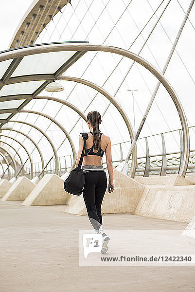 Sportive woman with sports bag walking  rear view