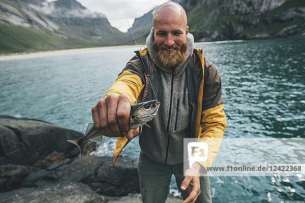 Norway  Lofoten  Moskenesoy  Young man holding freshly caught fish