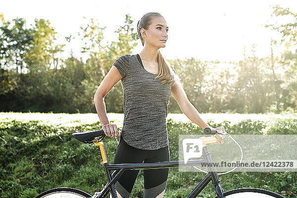 Sportive young woman with bicycle in nature