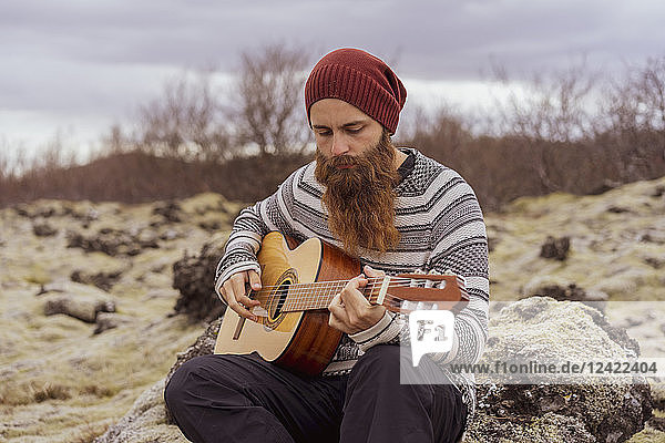 Man sitting in wilderness  playing the guitar