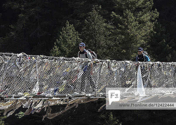 Nepal  Solo Khumbu  Everest  Sagamartha National Park  Two people crossing suspension bridge
