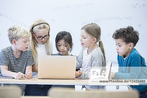 Pupils with laptop learning together in class