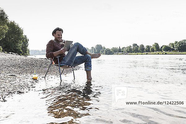 Mature man using tablet at Rhine riverbank