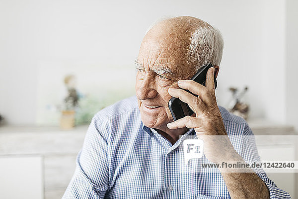 Happy senior man using smartphone at home