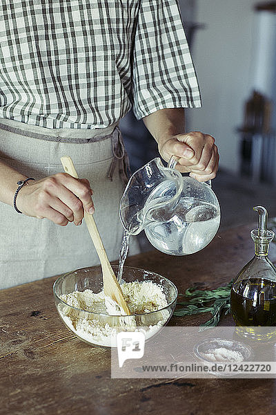 Young woman in kitchen preparing dough for fresh chickpea cake
