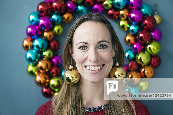 Portrait of smiling woman wearing golden Christmas bauble earrings