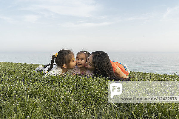 Mother with two daughters kissing at the coast