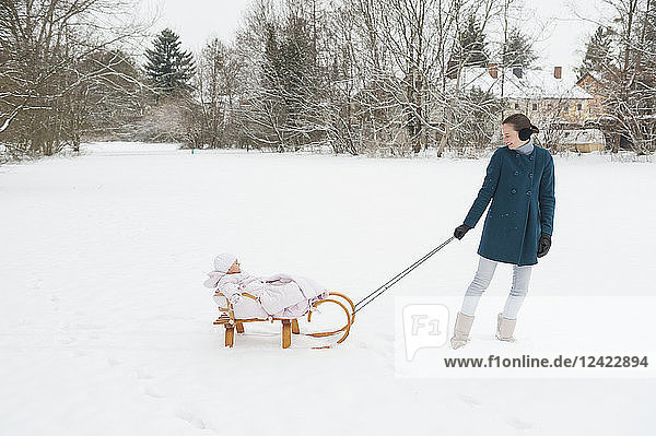 Mother pulling little daughter on sledge