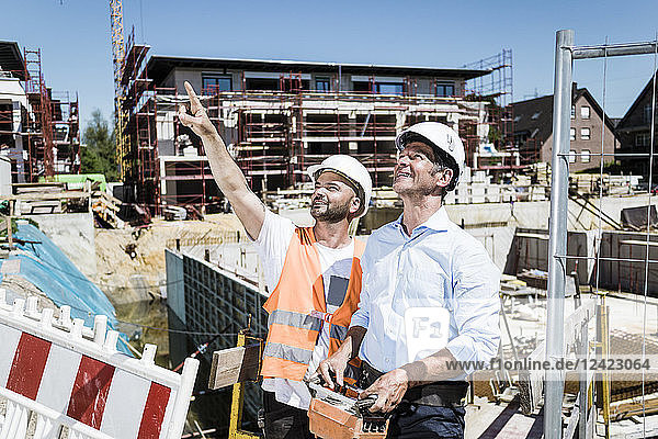 Smiling construction worker talking to man on construction site