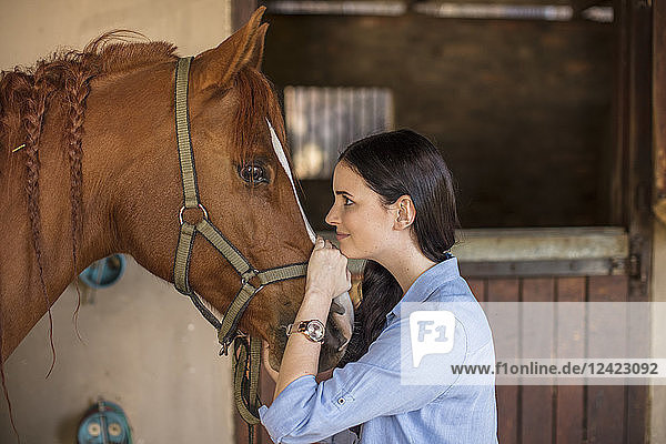 Smiling woman caring for a horse on a farm