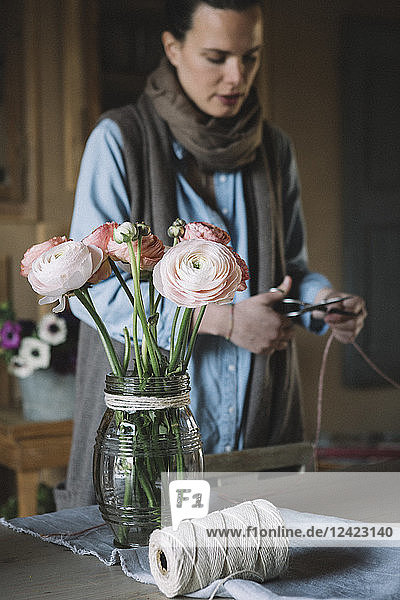 Woman arranging fresh flowers  cutting cord