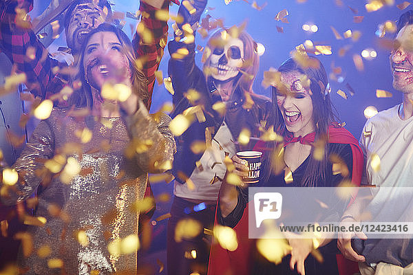 Friends in Halloween costumes dancing among confetti