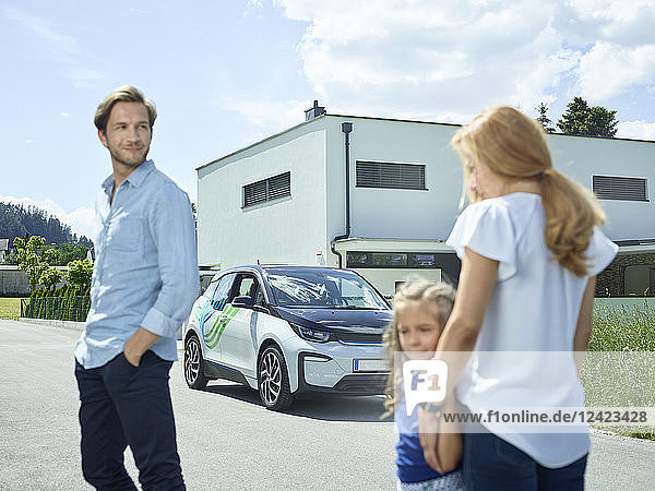 Family with electric car in front of house