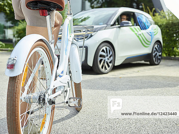 Woman with bicycle in front of electric car