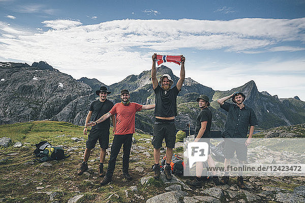 Norway  Lofoten  Moskenesoy  Group of young men cheering with Norwegian flag