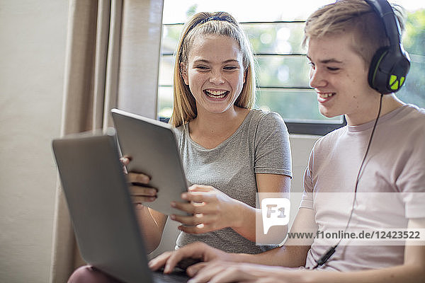 Happy boy and teenage girl with tablet  laptop and headphones