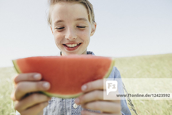 Happy boy on a field eating a watermelon