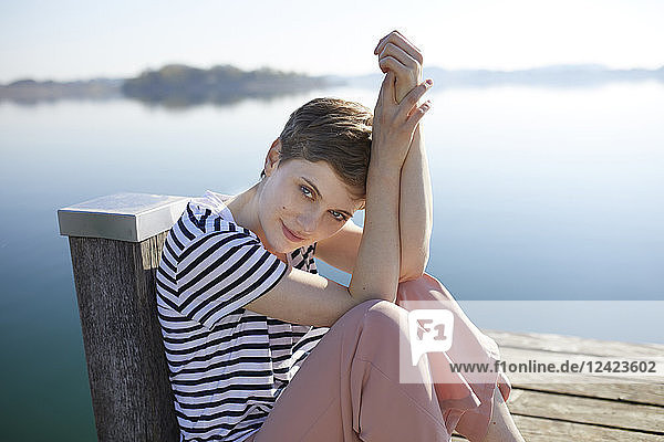 Portrait of woman sitting on jetty at lake