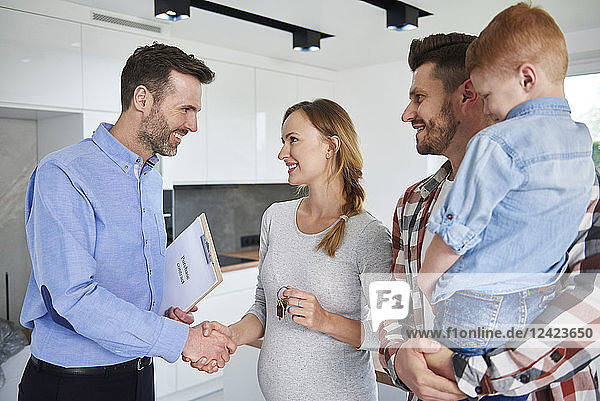 Family and real estate agent shaking hands in new apartment