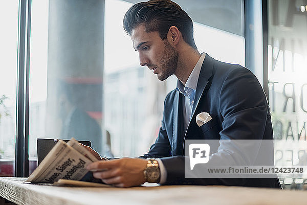 Young businessman reading newspaper in a cafe