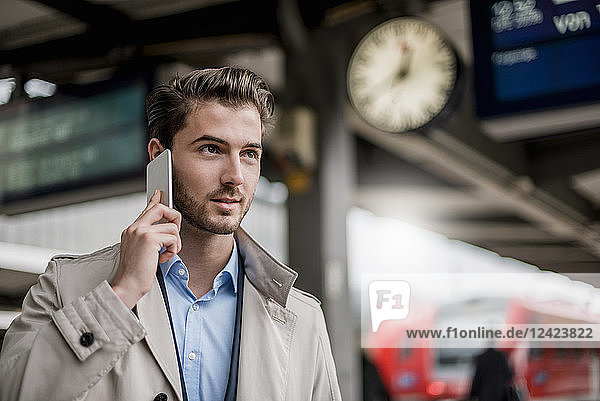 Businessman at the station on cell phone