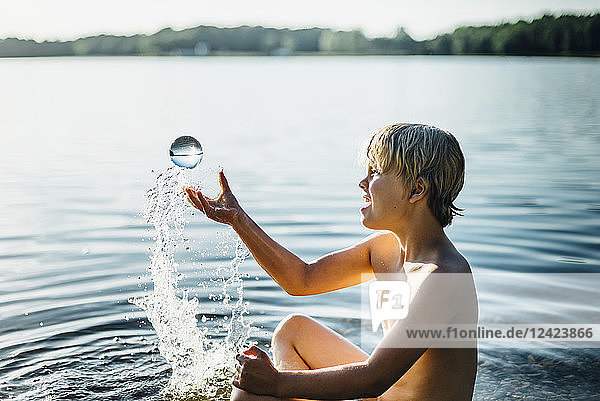 Boy in a lake playing with tansparent sphere