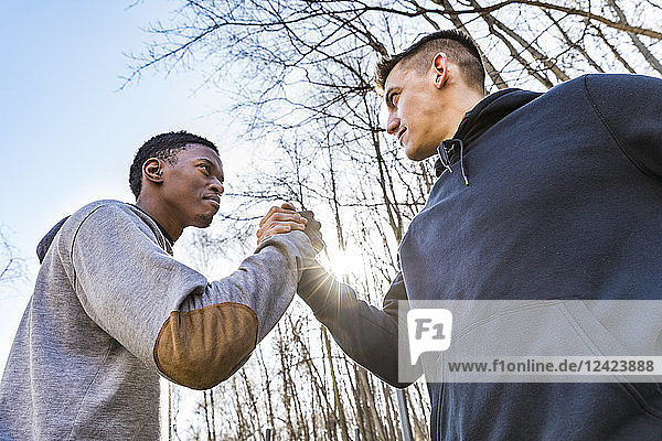 Two sportive young men shaking hands outdoors