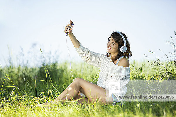 Smiling young woman with earphones taking a selfie