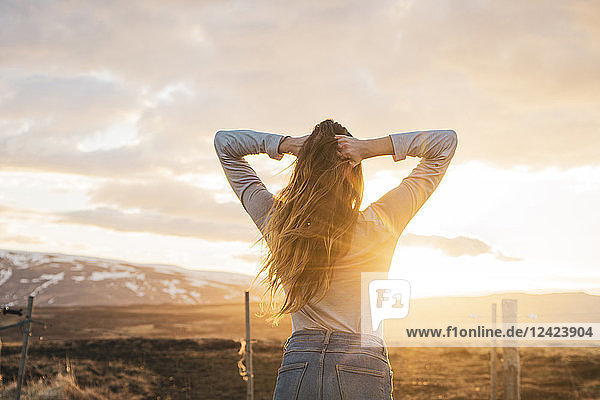 Iceland  young woman with hands in hair at sunset