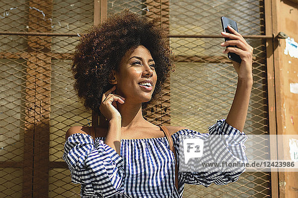 Smiling young woman taking selfie with cell phone