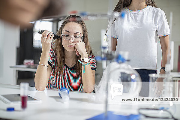 Teenage girl with cell phone in science class