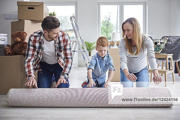 Family unrolling a carpet in new flat