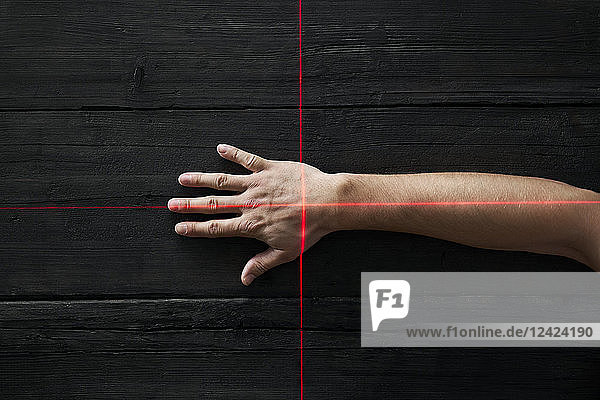 Human hand getting scanned by red light rays