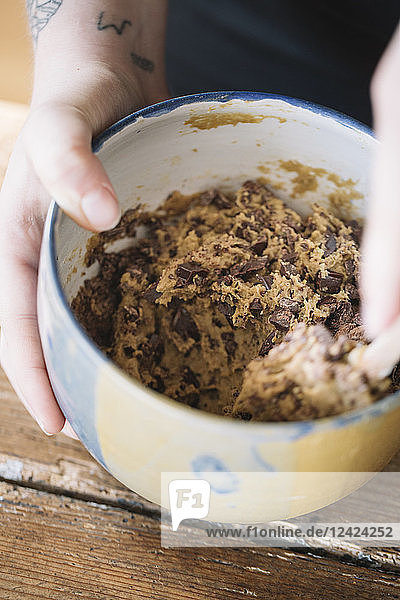 Woman's hand holding bowl of prepared batter for homemade vegan chickpea cookies  close-up