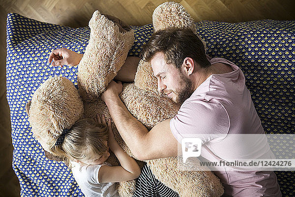 Father and daughter taking a nap  cuddling with teddy bear