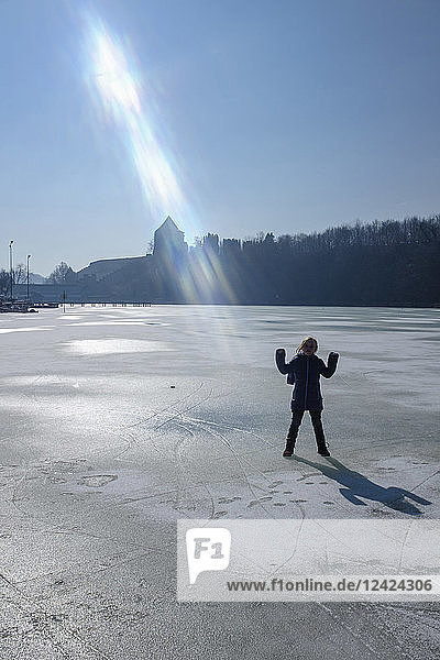 Girl standing on frozen lake  sun beam