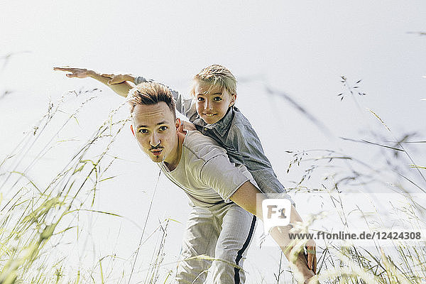 Young man and boy in a field pretending to fly