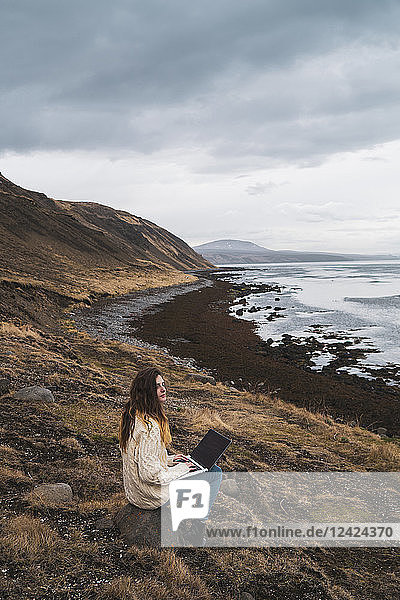 Iceland  woman using laptop at the coast