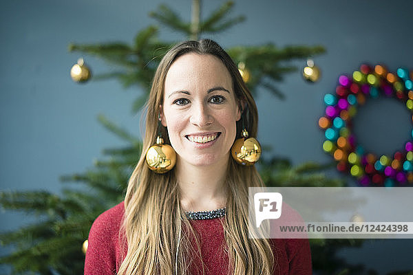 Portrait of smiling woman wearing golden Christmas baubles earrings