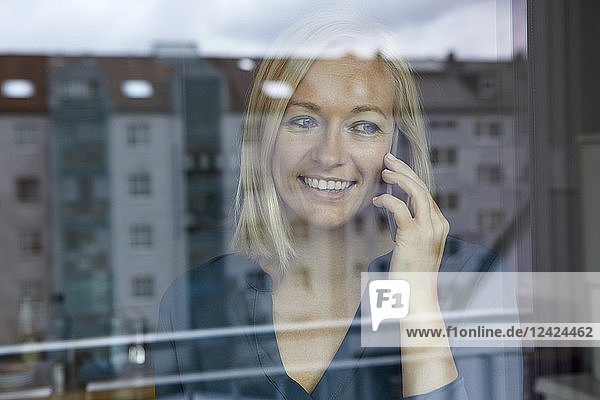 Blond woman standing at window  talking on the phone