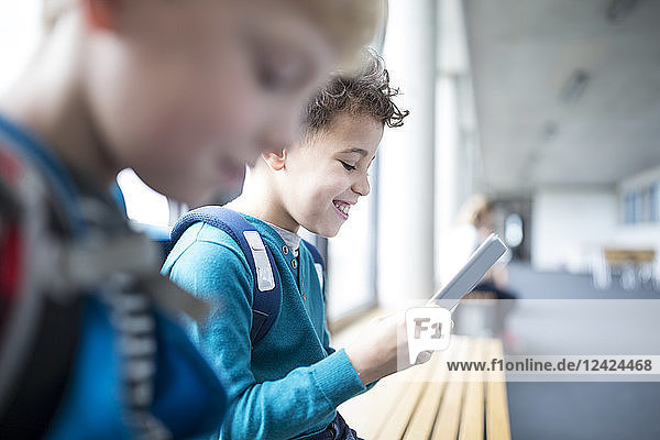 Smiling pupils with tablet on school corridor