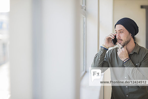 Young man on cell phone at the window in office