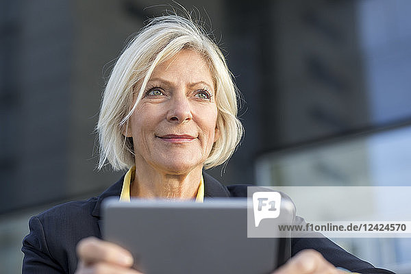 Portrait of smiling senior businesswoman with tablet outdoors