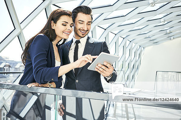 Businesswoman and businessman sharing tablet in modern office