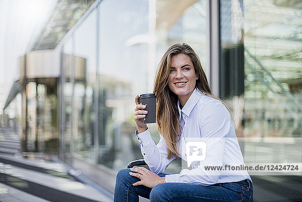 Portrait of smiling young businesswoman with coffee to go