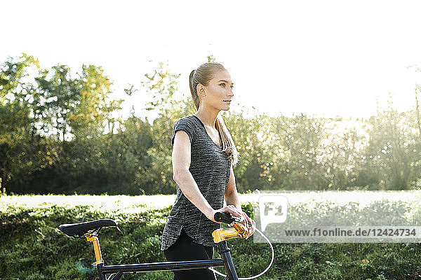 Sportive young woman with bicycle in nature