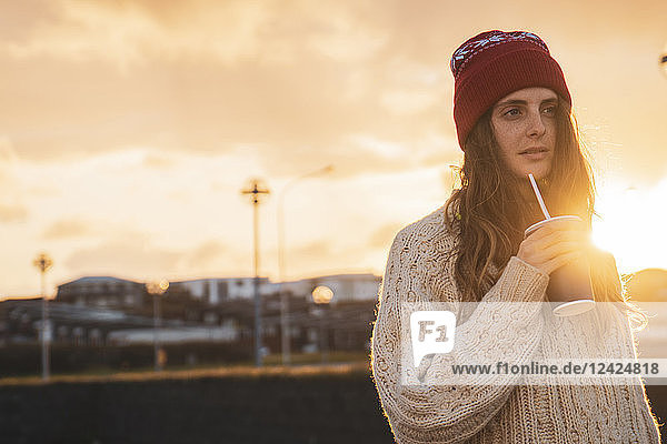 Iceland  young woman with coffee to go at sunset