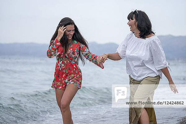 Greece  mother and adult daughter iwalking hand in hand at seaside