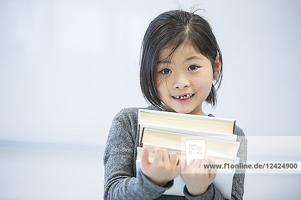 Portrait of smiling schoolgirl carrying books in class